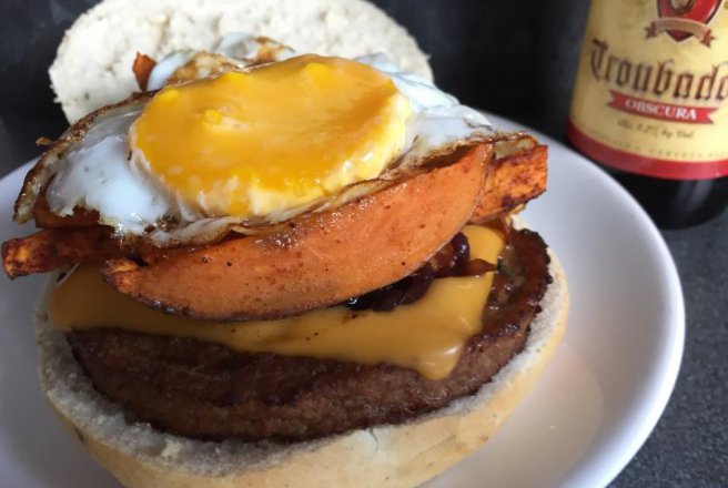 Burger vegetarian cu ou prajit, cartofi dulci si ceapa caramelizata in bere